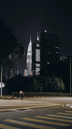 Nighttime view of a traveler safely navigating a quiet street with illuminated landmarks.
