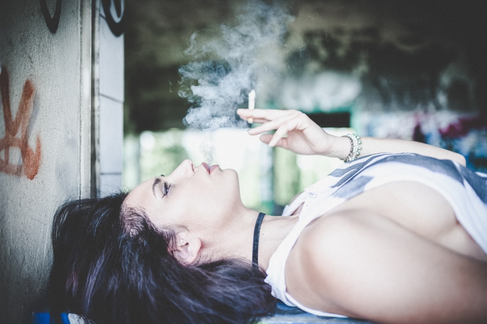 woman smoking cigarette while lying