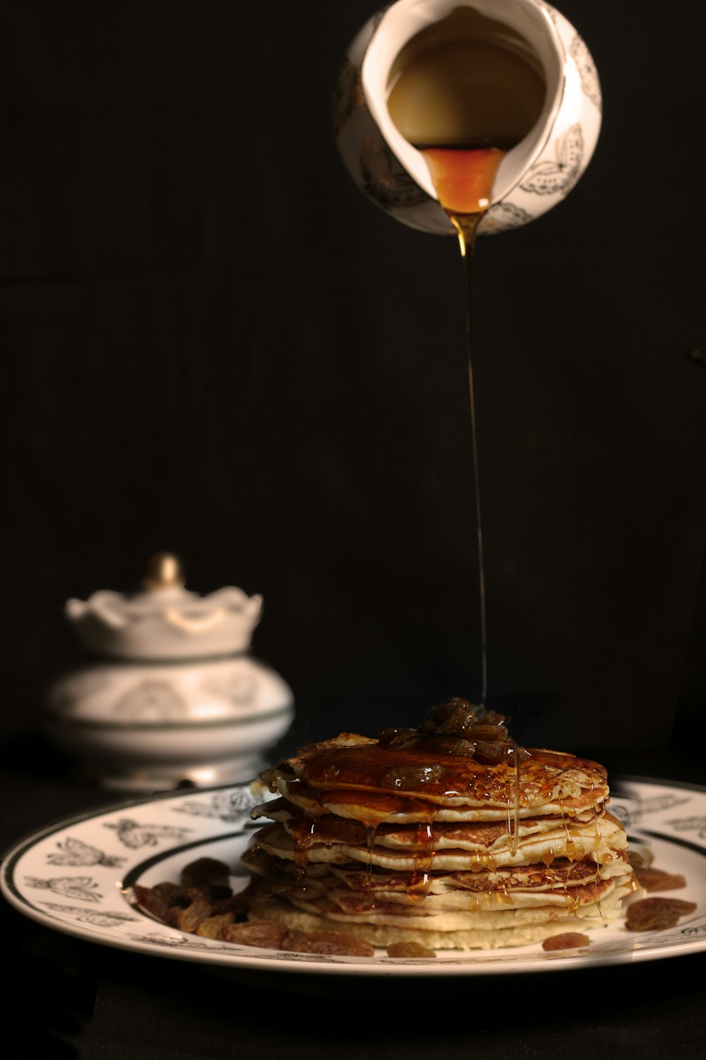 person pouring honey on pancakes