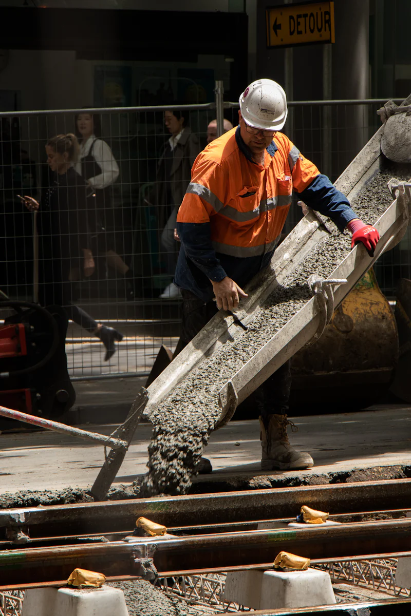 Worker pouring concrete down a chute onto a street-level repair