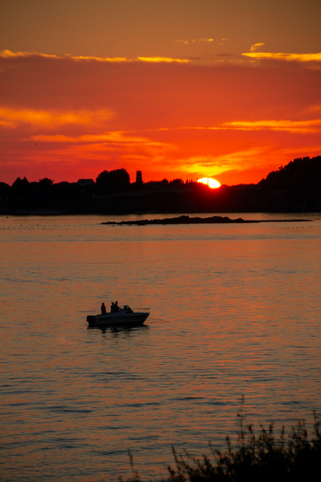 people in boat on body of water under orange sky