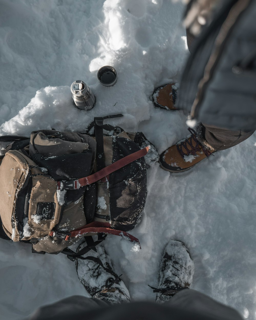 two people standing on snow near backpack