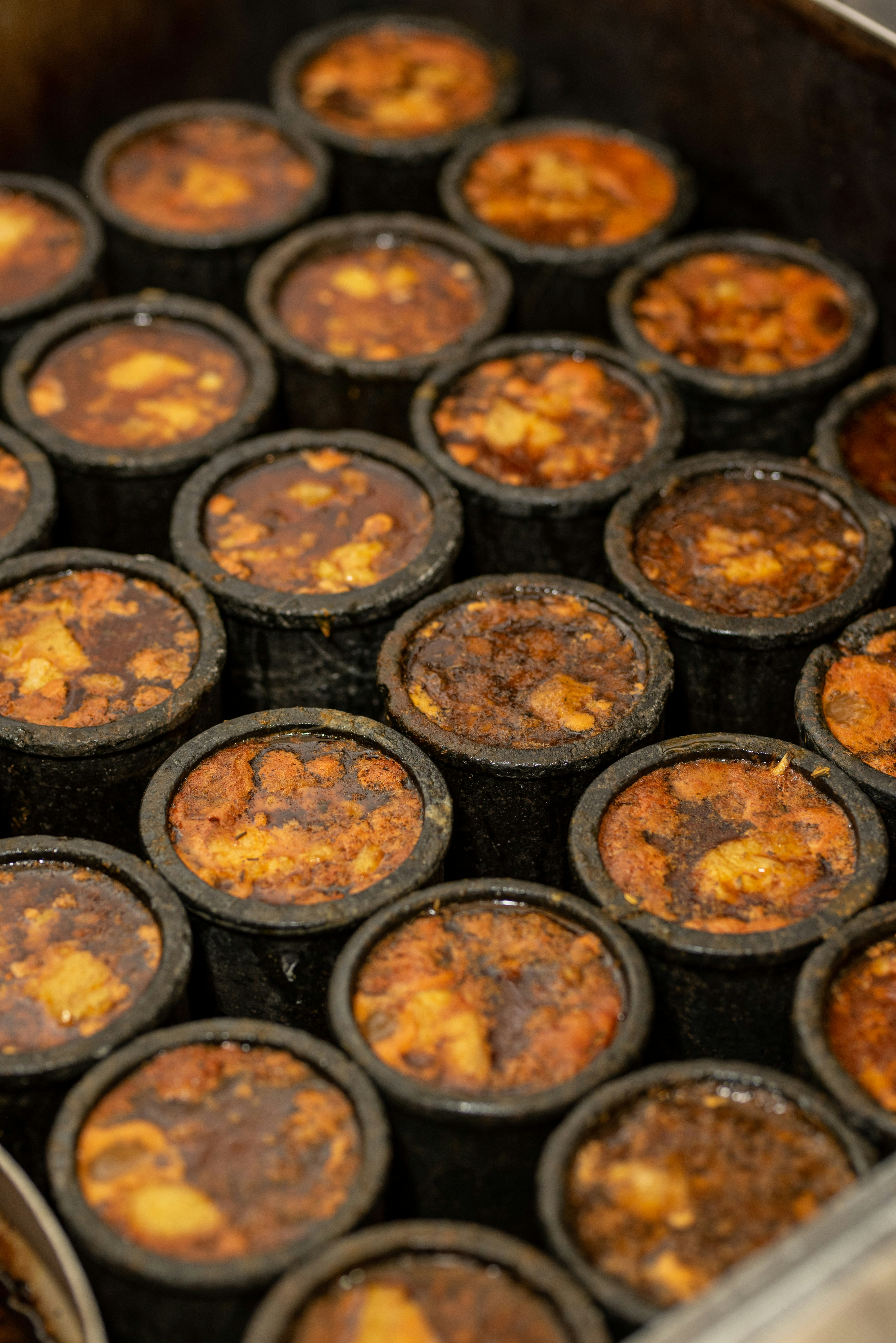Multiple Yorkshire puddings baking in a dark oven, golden-brown tops visible in individual tins