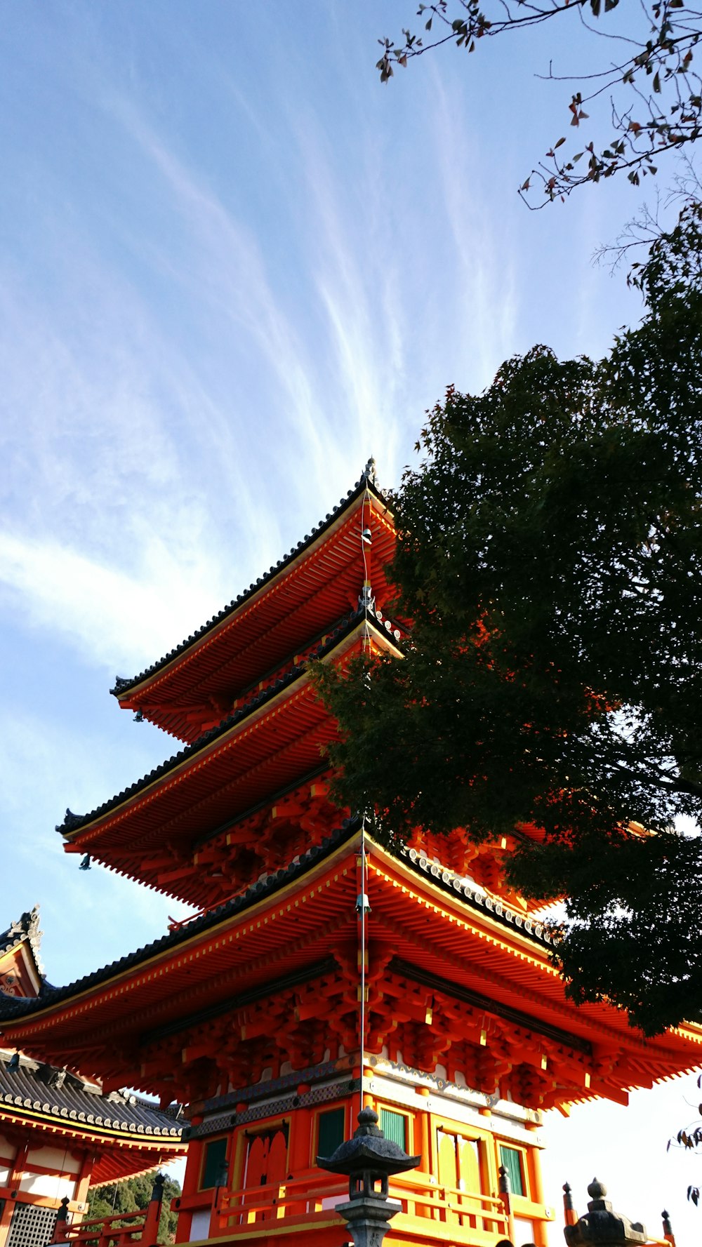 red and brown pagoda temple beside trees