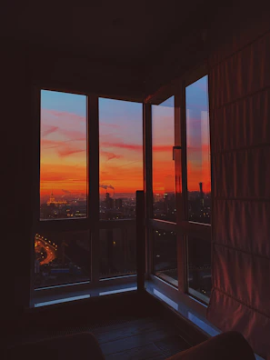 A vibrant cityscape at sunset viewed from an office window where news is being prepared.