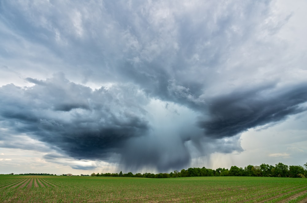 landscape photography of a green field under a cloudy sky