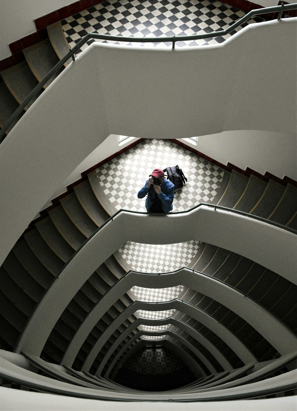 high-angle photo of man standing in front of balustrade of staircase