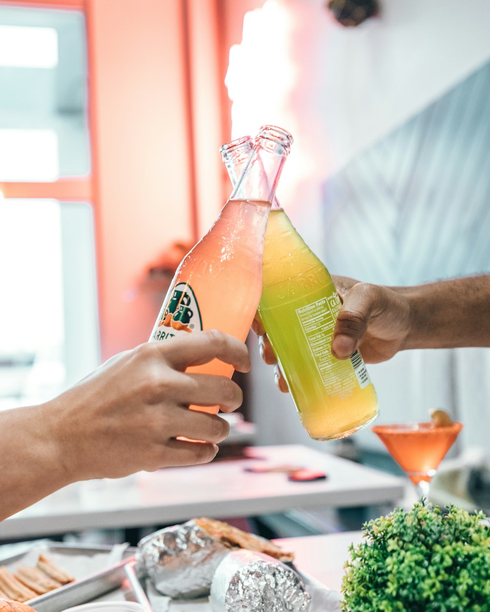 two people toasting with glass bottles