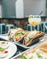 three tacos on plate beside margarita for tour