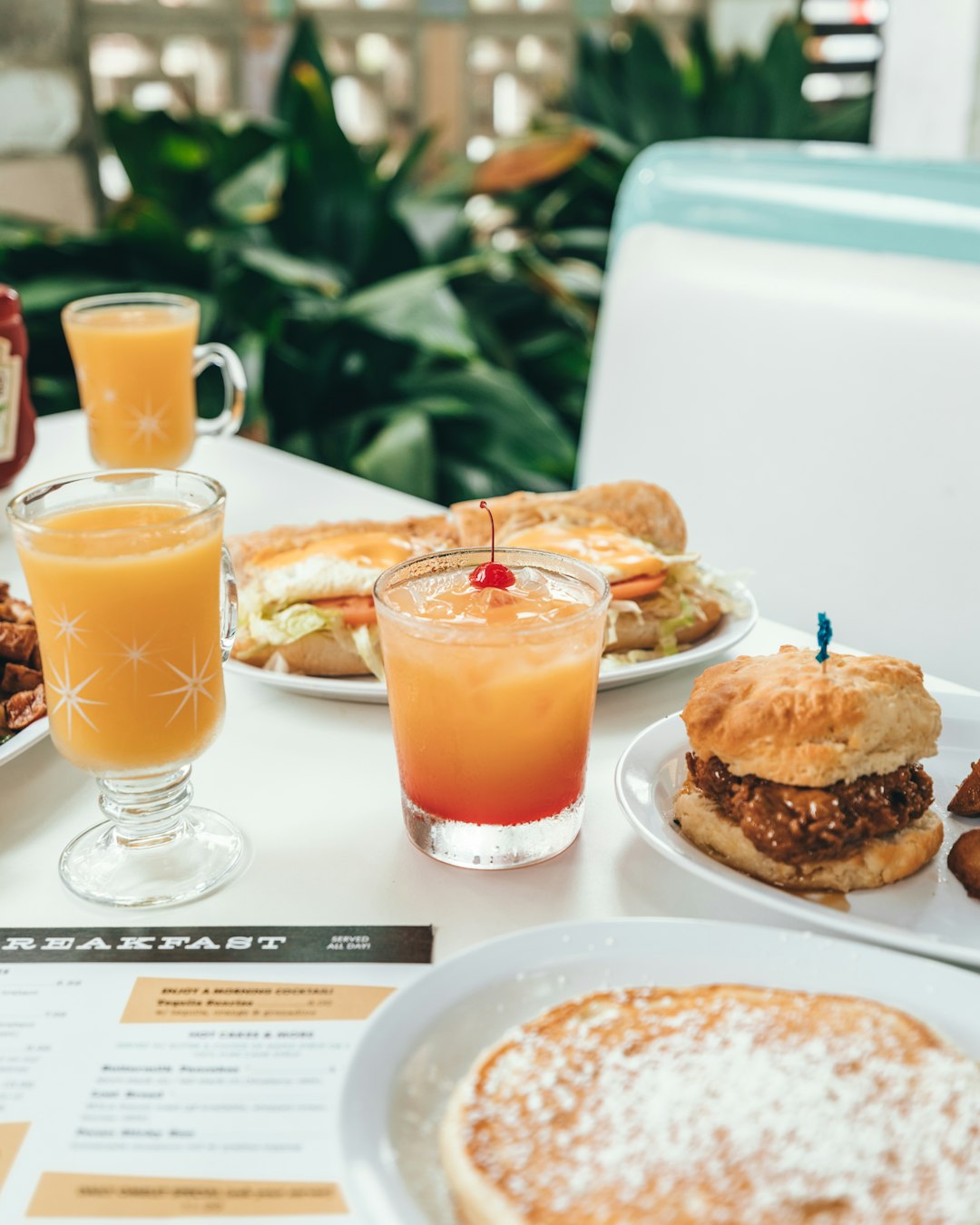 cup of juice beside plate of burger and sandwich