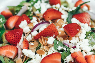 A bright and fresh salad bowl with arugula, strawberries, feta cheese, and a balsamic glaze.