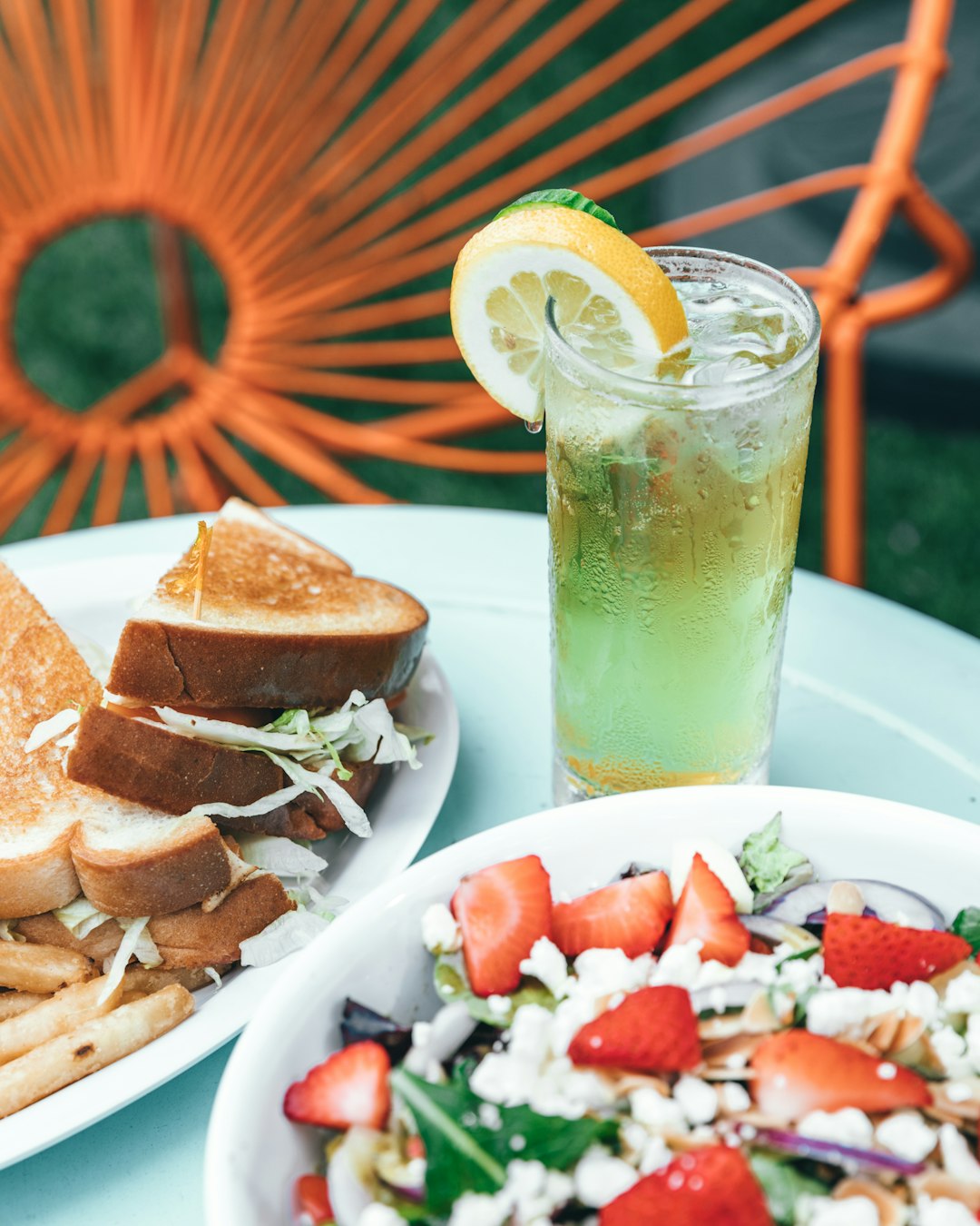 glass of juice in between of salad vegetable and plate of toasted bread