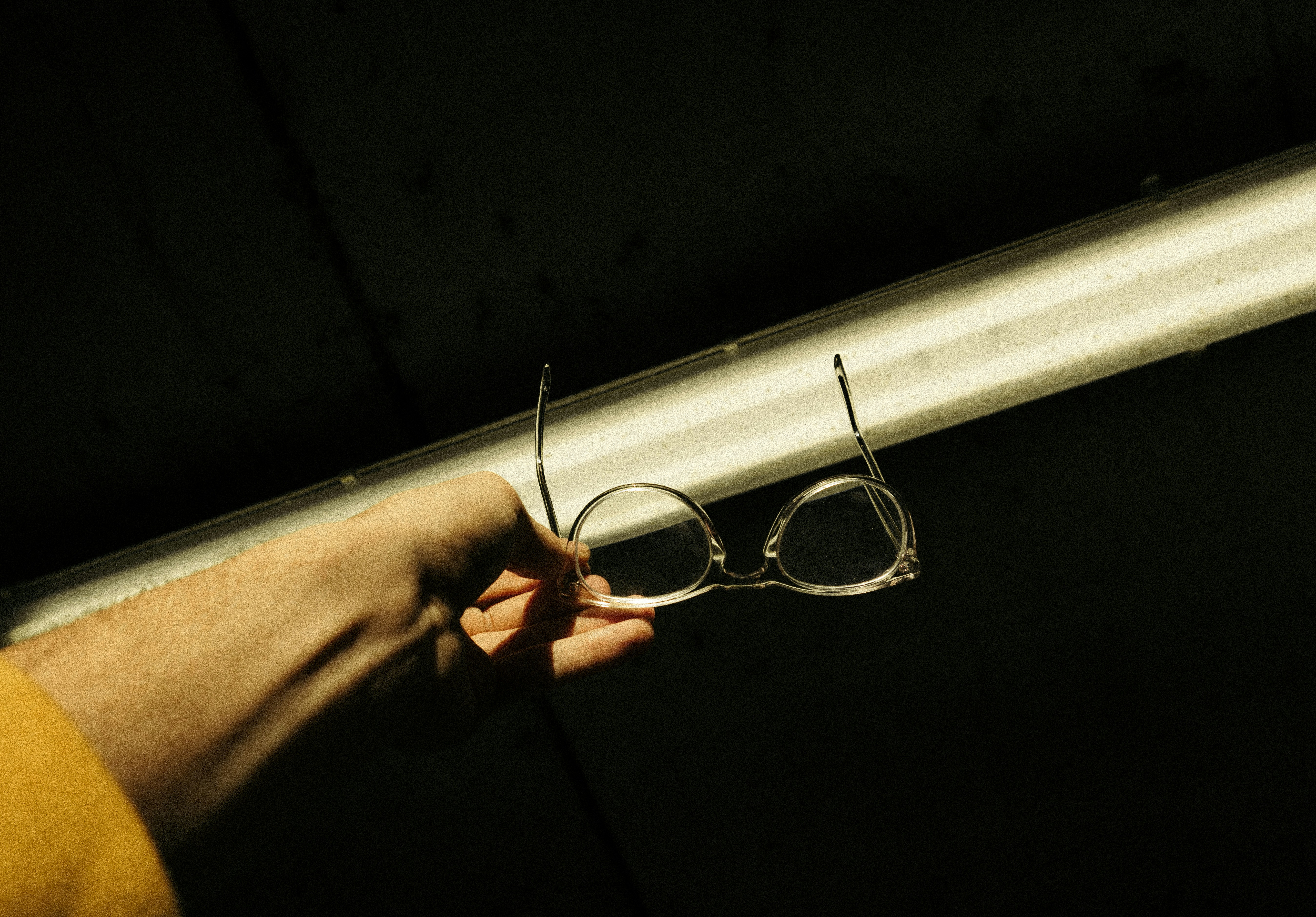 selective focus photo of person holding clear-framed eyeglasses