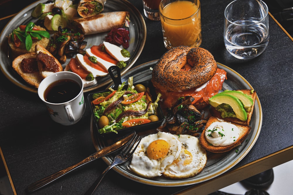 hamburger, fried eggs, avocado slices, and bread on round gray plate