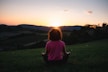 woman squatting in grass during golden hour