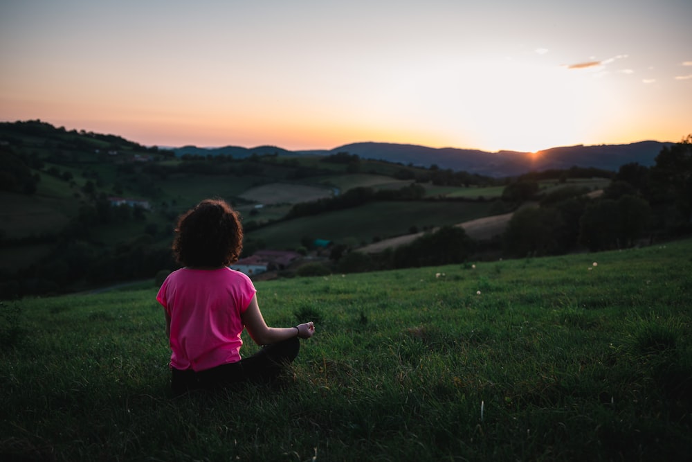 donna che si siede sul campo d'erba durante il giorno