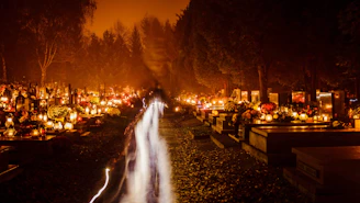 Close-up of golden and burgundy candles glowing softly on a granite tombstone.