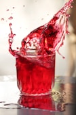A vibrant splash of Enemy Ender soda pouring into a glass with ice.