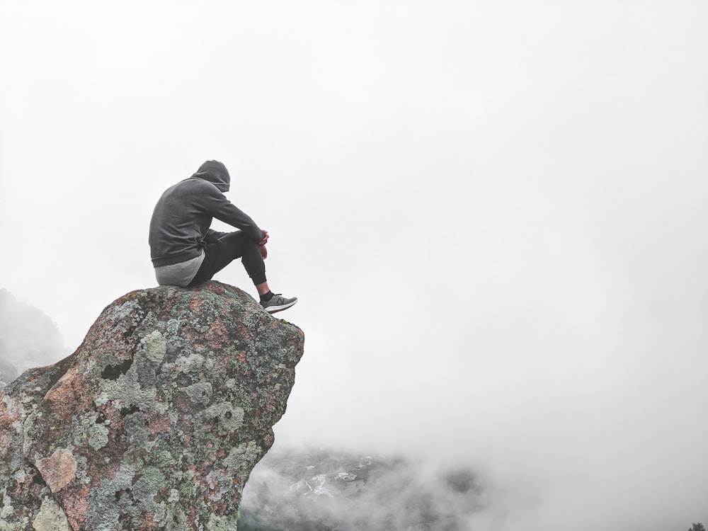 person in gray hoodie standing on rock