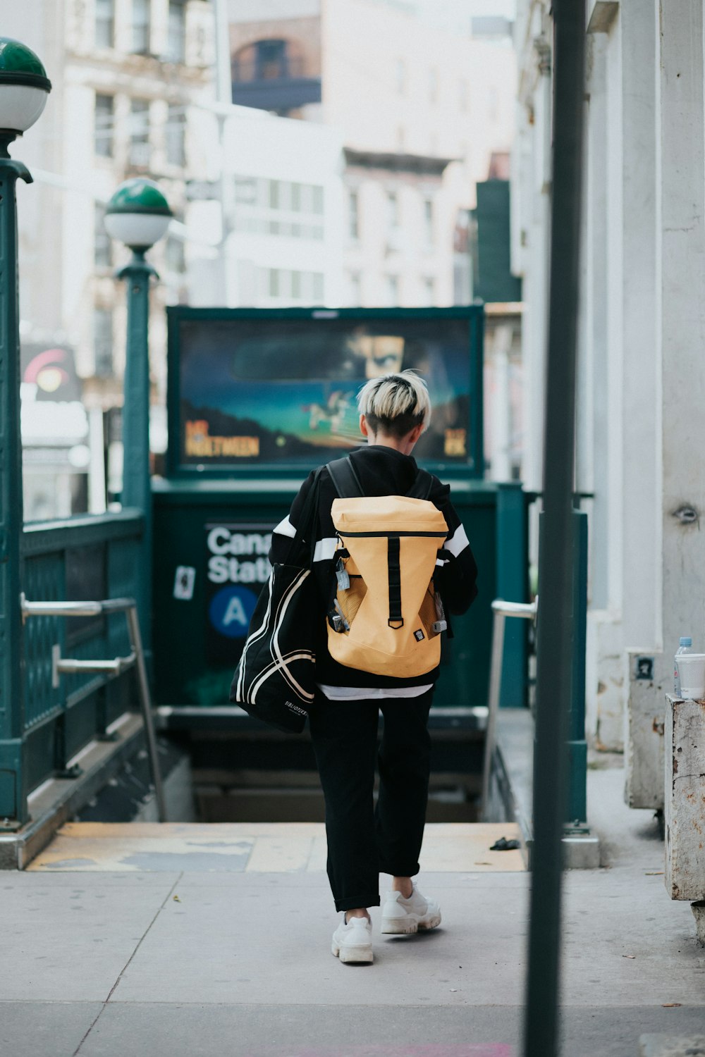 a person with a back pack walking down a sidewalk