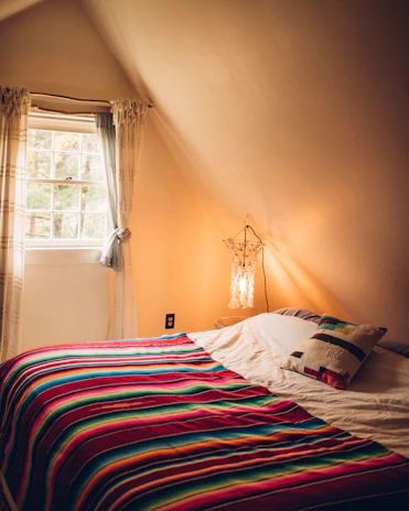 A cozy bedroom ceiling illuminated by the rotating star projector lamp casting vibrant star patterns.