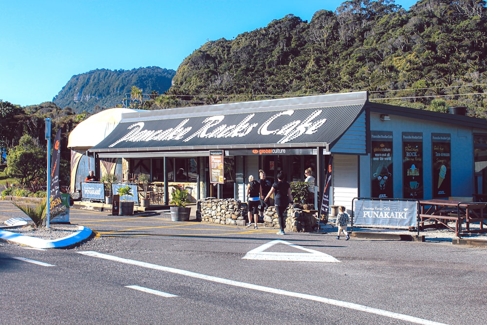 people standing beside rocks cafe during daytime