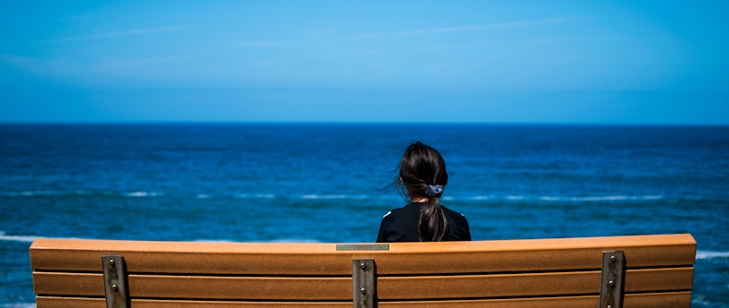 woman wearing black top sitting on brown bench chair