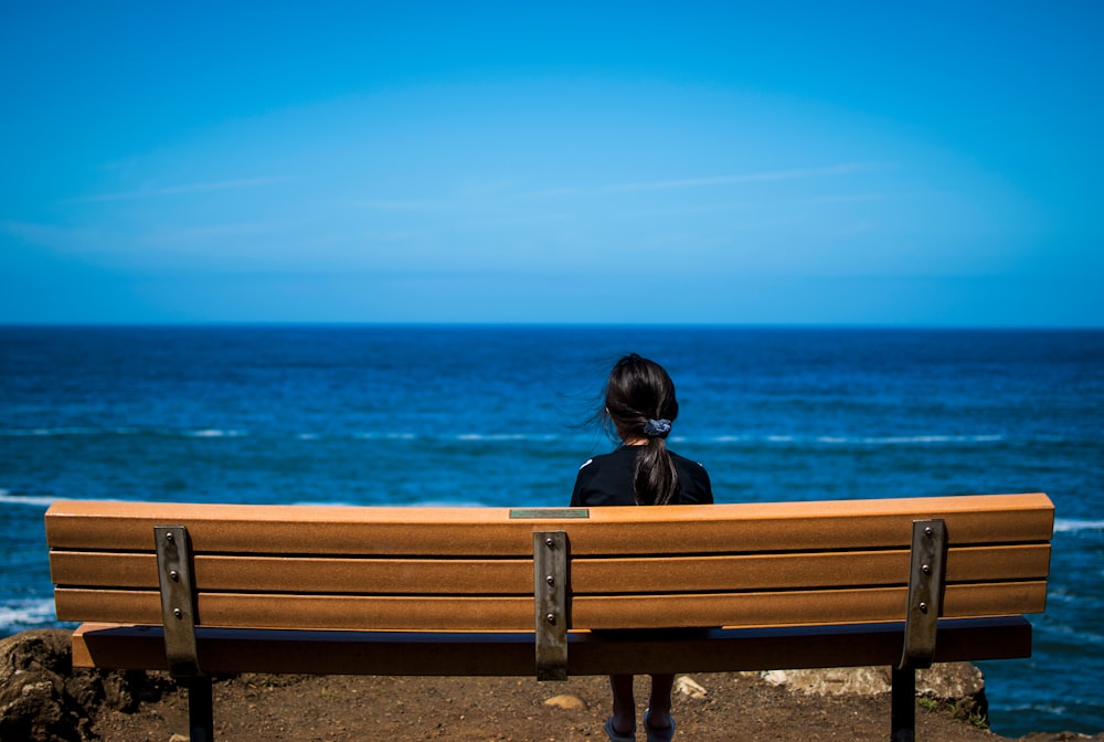 woman wearing black top sitting on brown bench chair