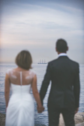 Couple walking hand in hand along the ship’s promenade, framed by the deep black sea and sky.