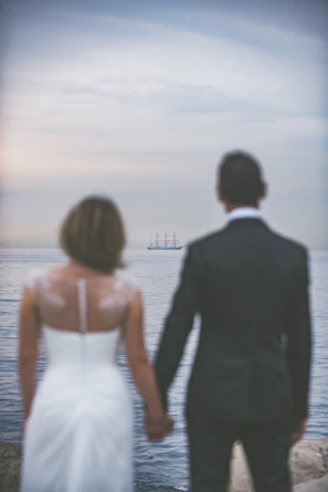 Close-up of a couple holding hands on the ship’s balcony, overlooking the endless blue ocean.