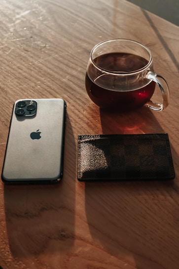Close-up of a sleek cup resting on a wooden table next to a smartphone showing a social media post.