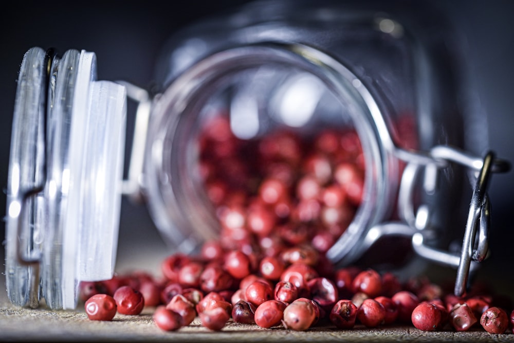 macro photography of red fruit lot in jar