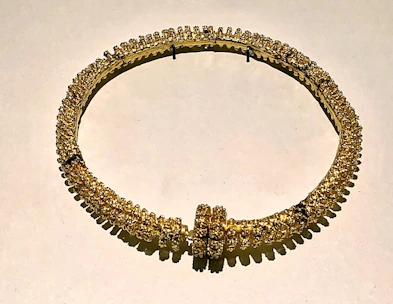 Elegant gold necklace with intricate design displayed on a wooden surface