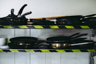 Close-up of a multi-tier rack with neatly stacked pots and pans in a modern kitchen.