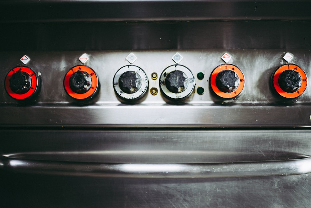 a close up of a metal stove with four knobs