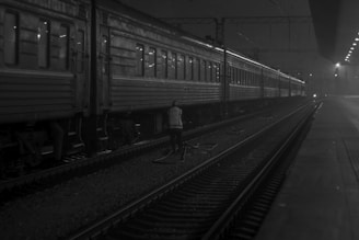 grayscale photo of person walking near train