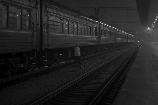 grayscale photo of person walking near train