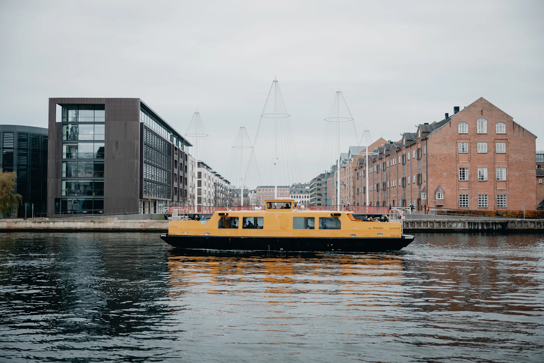 A yellow Copenhagen passenger boat crosses the harbour.