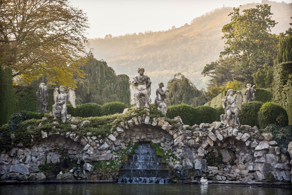 statues beside body of water during daytime