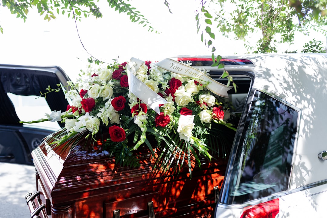 funeral details of flowers on cherry wood casket and white car