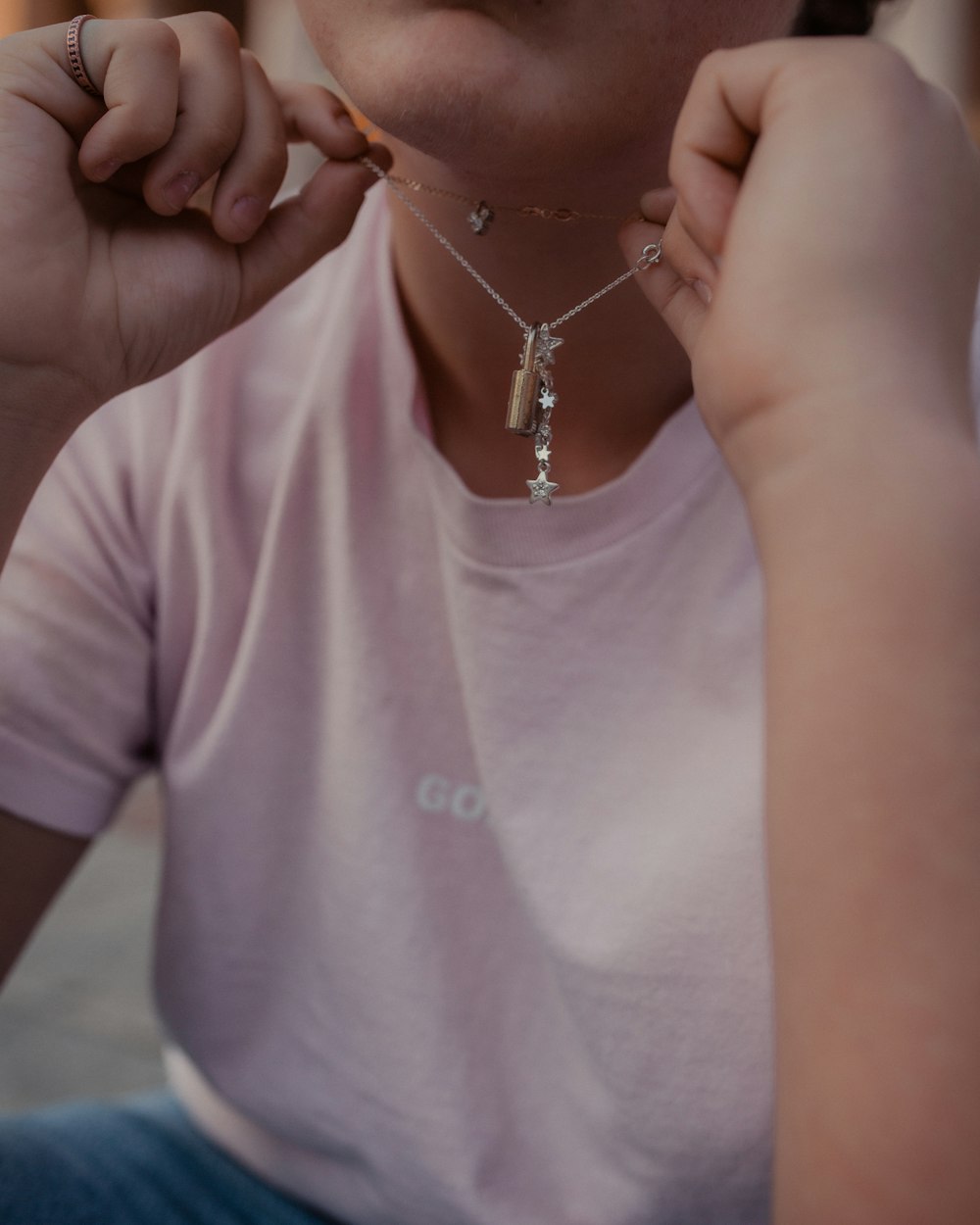 person holding the silver-colored necklace