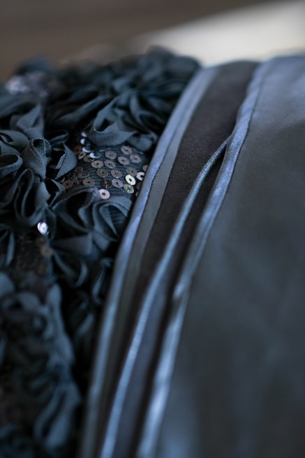 Close-up of luxurious black fabric with delicate stitching and subtle shimmer.