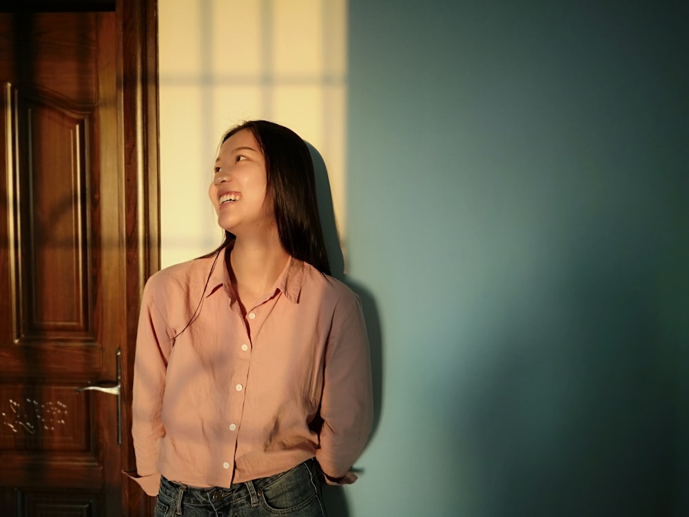 woman in pink dress shirt standing beside doorr