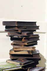An artful stack of vintage books with surreal covers and odd titles.