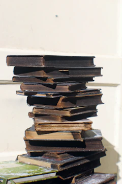 An artful stack of vintage books with surreal covers and odd titles.