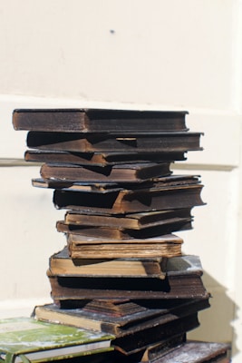 Stacks of second-hand books with worn covers arranged next to a model semi-truck on a wooden table.