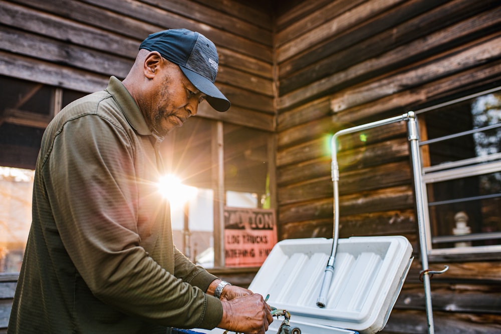 man wearing green sweater and blue cap holding white chiller