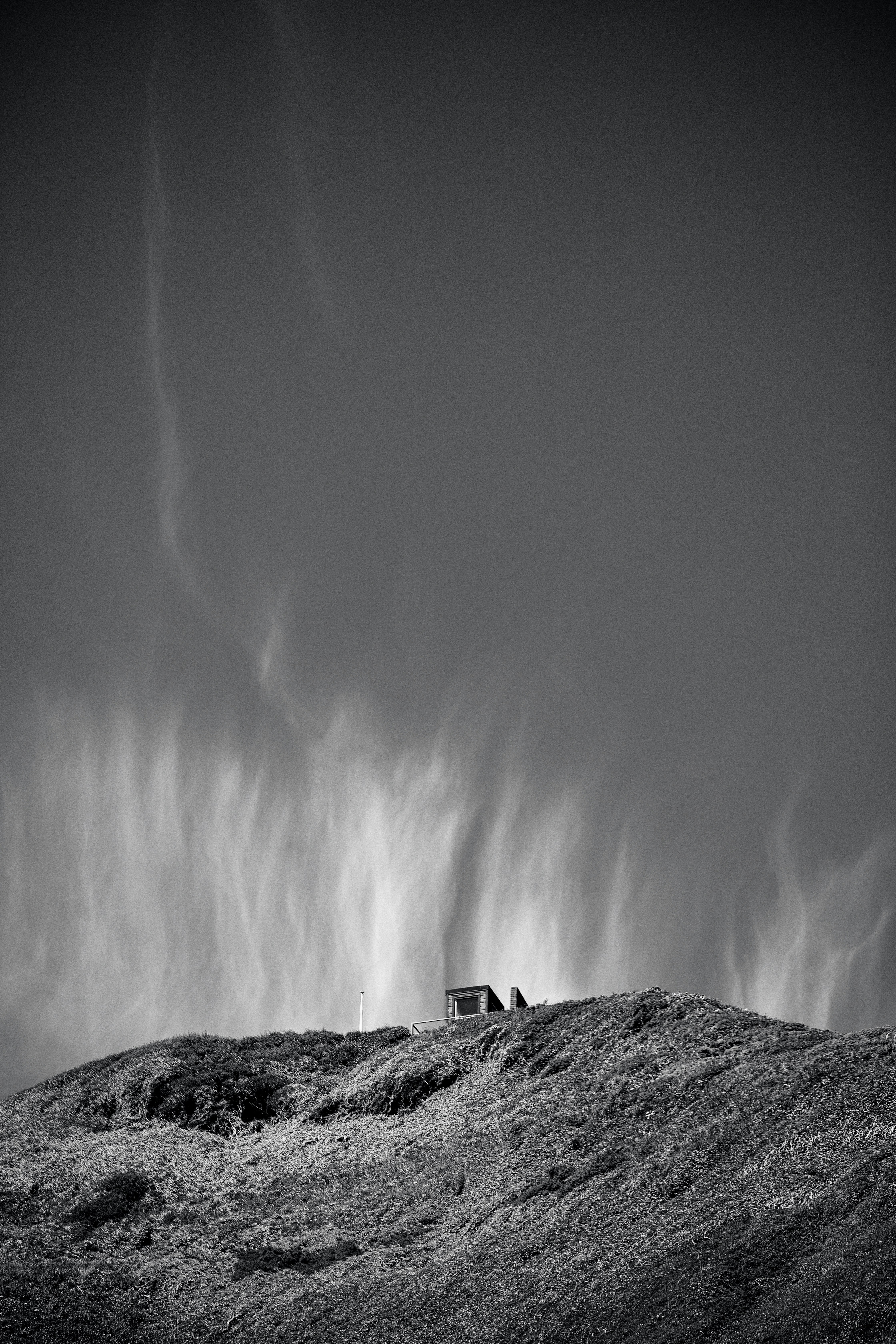 Foto in scala di grigi della casa nel mezzo del campo di erba di montagna