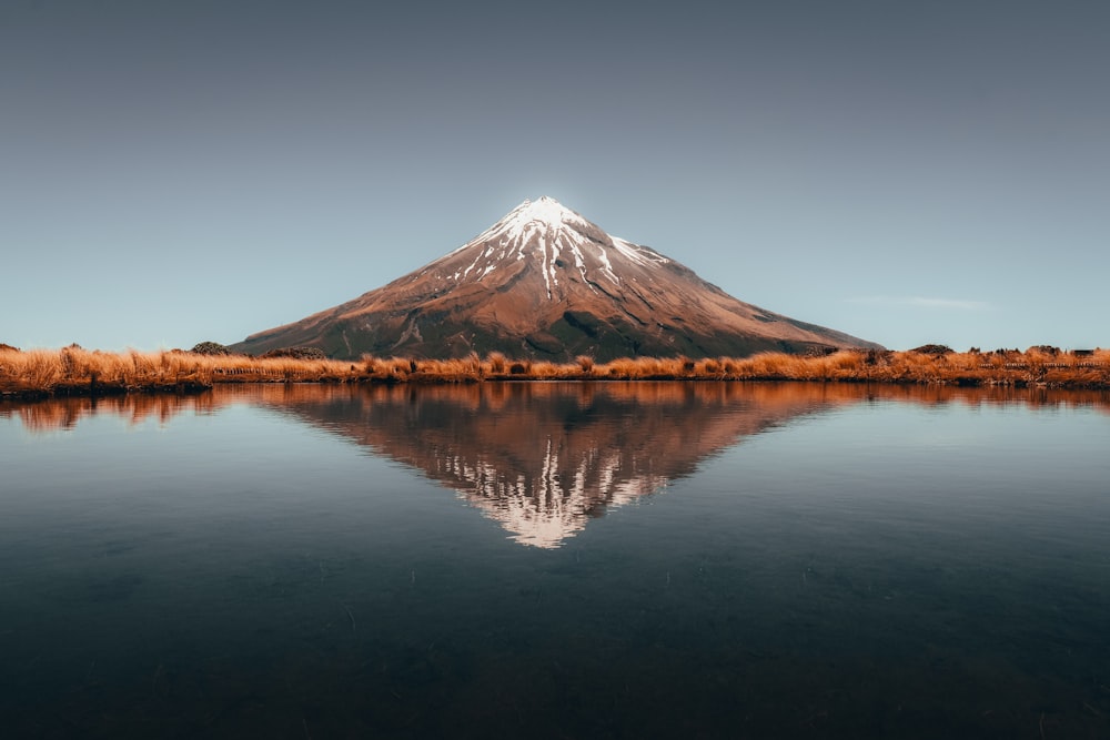 a mountain is reflected in the still water of a lake