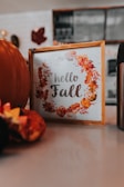 hello fall sign in frame on white surface with a fall decor